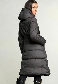 Černý prošívaný kabát s kapucí, se staženým pasem a zvonovým lemem. Hladká textura, prošívaný design a lehký materiál.