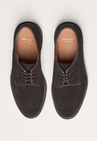 Braune Wildlederschuhe mit runder Spitze, dekorativen Nähten und Schnürdetails. Hergestellt in Spanien, mit einem glatten Lederinnenfutter.