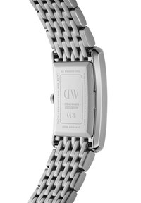 Montre en acier inoxydable avec un boîtier rectangulaire et un bracelet en maille. Le dos gravé inclut les détails de la marque et du mouvement. Fini poli de ton argent.
