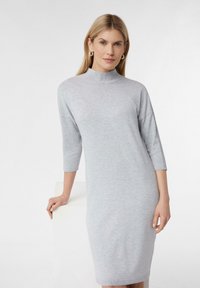 Helles graues Strickkleid mit hochgeschlossenem Ausschnitt und dreiviertellangen Ärmeln, das eine taillierte Passform und eine glatte Textur aufweist. Keine Muster oder Akzente.
