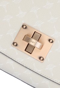 Sac à main en cuir blanc texturé, doté d'une fermeture en métal doré avec logo gravé et éléments décoratifs. Motif subtil sur toute la surface.