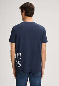 Marineblaue Kurzarm-T-Shirt mit Rundhalsausschnitt; verfügt über einen weißen Textgrafik auf der Rückseite, hergestellt aus weichem Stoff mit glatter Textur.