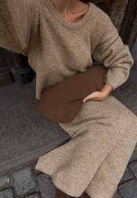 Beige kudum sweater laia kaelusega ja veidi puffsete varrukatega, millele on lisatud pruuni sametist käekotiga. Tekstuuriga kangas, mugav istuvus.