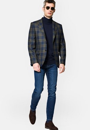 Marynarski niebiesko-zielony blazer w kratę noszony na niebieski golf, w połączeniu z niebieskimi dżinsami i brązowymi butami, charakteryzujący się dopasowanym krojem i wyrazistą sylwetką.