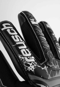 Guanti da calcio neri con un design strutturato, caratterizzati da una combinazione di superfici lisce e decorative, dita rinforzate e un marchio distintivo.