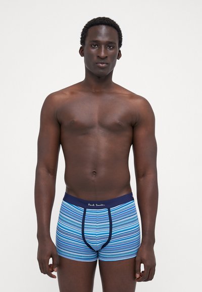 Caleçons boxers rayés aux teintes bleues et turquoises, avec une ceinture navy portant l'inscription "Paul Smith." Le tissu semble lisse et ajusté.