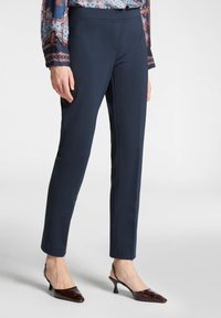 Meriputih yang dirancang khusus dengan tekstur halus dan potongan ramping, dilengkapi dengan pinggang elastis. Dipadukan dengan sepatu hak tinggi berbentuk runcing berwarna cokelat yang berlapis.