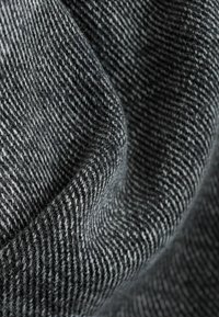 Tissu en laine gris foncé plié, avec un motif de tissage à fines rayures diagonales, montrant la texture et un tombé doux.