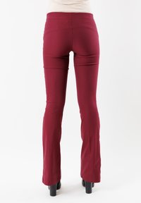 Pantaloni a zampa d'elefante in una profonda tonalità bordeaux. Realizzati in tessuto elasticizzato, con una texture liscia. La vita è senza cuciture e alta.