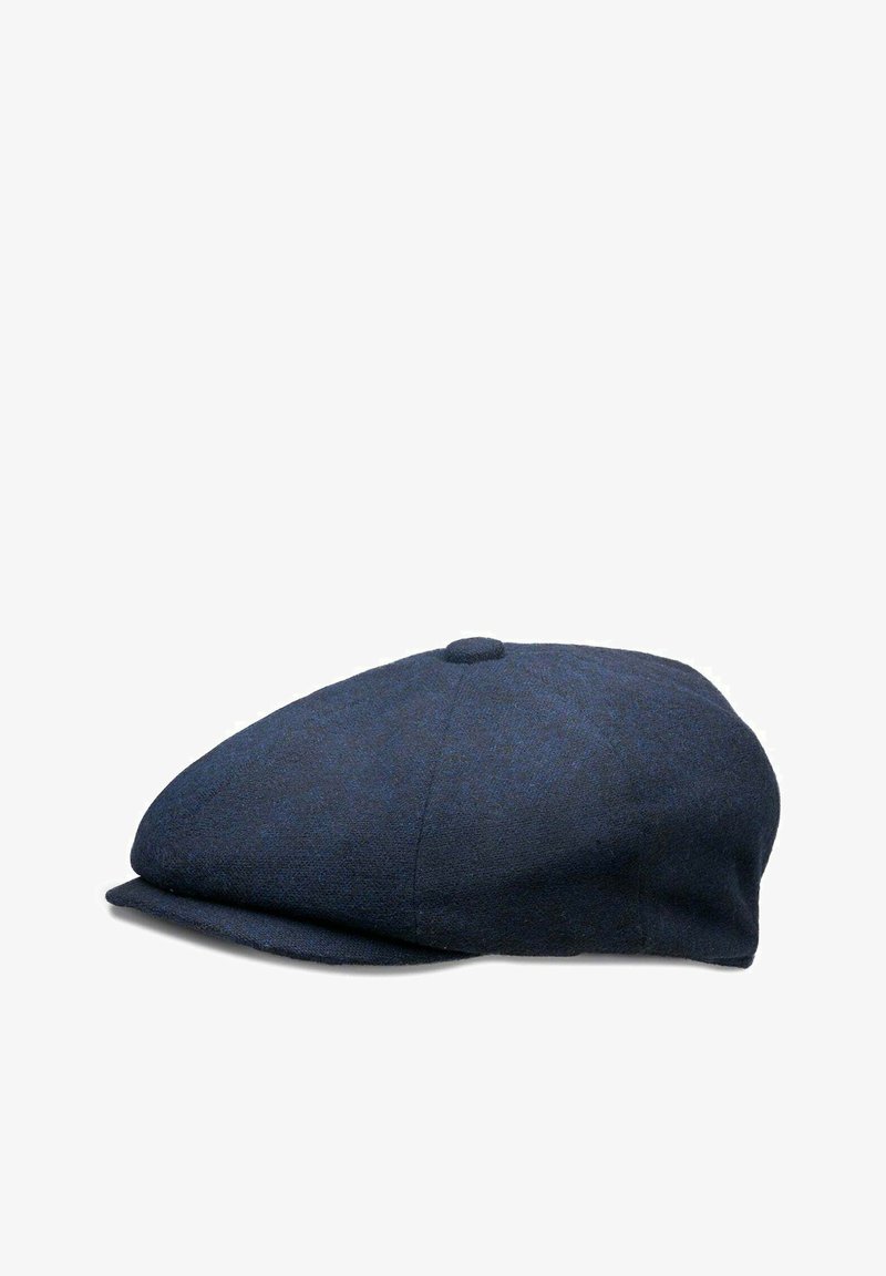 Navy wool flat cap features a round crown, a short stiff brim, and a textured fabric with a subtle pattern. It includes a center top button.