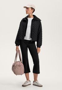 Mustat päällystetyt bomber-takit, valkoinen pitkähihais t-paita, mustat lyhyet housut, vaaleanpunainen paksu laukku ja harmaat lenkkarit. Asusteina on vaalea lippis.