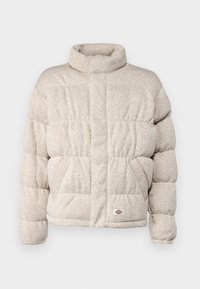 Beige puffjacka med hög krage, quiltrad design och en logotyp på nedersta vänstra delen. Tillverkad av textil med värmande egenskaper.