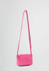 Růžová kožená crossbody taška s obdélníkovým tvarem, nastavitelného popruhu a hladkým povrchem. Má zipové zapínání a minimalistický design.