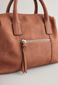 Braune Leder-Handtasche mit strukturiertem Oberflächen, doppelten Griffen und einer vorderen Reißverschlusstasche mit Leder-Pull-Tab.