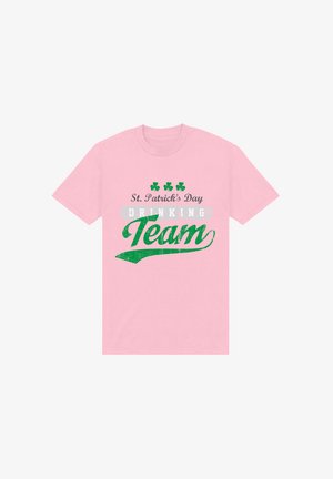 Rosa bomulds T-shirt med grønt tekst, der står "St. Patrick's Day Drinking Team" og med kløver grafik samt et slidt trykstyle.