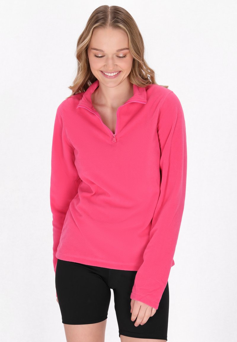 Pullover in pile rosa con colletto a mezza zip, texture morbida e maniche lunghe, abbinato a pantaloni corti neri aderenti. Design semplice, senza motivi.