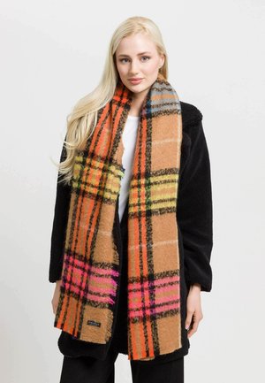 Brunternede plaid-scarf med livlige orange, pink og grønne detaljer. Blød tekstur og frynser i kanten, båret over en sort frakke.
