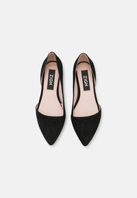 Ballerine nere in suede con punta a punta e lati a taglio, con una morbida fodera interna. Presentano un'etichetta del marchio "ZIGN" visibile all'interno della scarpa.