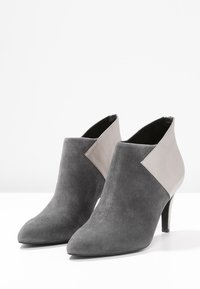 Stivaletti ankle in suede grigio con punta affusolata, dotati di un pannello laterale in un grigio chiaro a contrasto e un sottile tacco a stiletto.