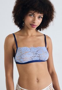 Bralette en dentelle bleu clair avec bordure bleu marine. Présente un motif floral, des bretelles ajustables et un design respirant.