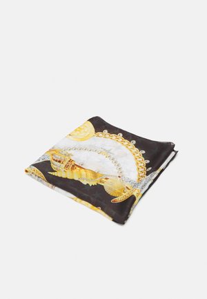 Gefalteter schwarz-weißer Schal mit goldener Kette, Perlenkette und Muschelmuster auf einfachem hellem Hintergrund.