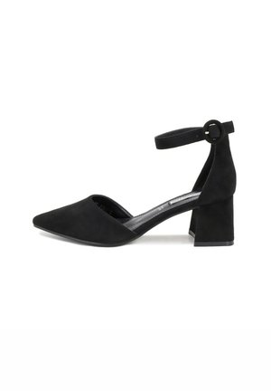 Décolleté nera in suede con cinturino alla caviglia, punta appuntita, tacco medio a blocco e fibbia circolare sul cinturino, caratterizzata da una texture liscia.