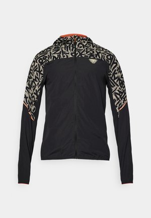 Černá lehká bunda s vzorovanou kapucí a rameny v béžové barvě s černými akcenty. Oranžové detaily na manžetách a zipu.