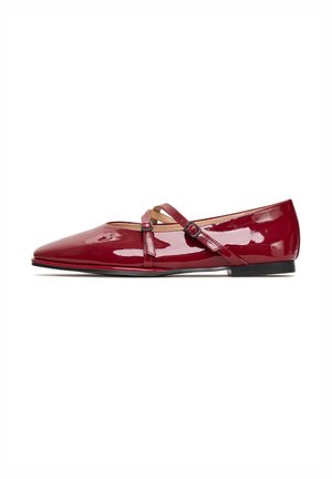 Zapatos planos de charol rojo con puntera puntiaguda y dos correas asimétricas que cuentan con hebillas ajustables. Superficie lisa y brillante con un ligero tacón.
