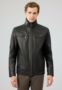 Zwart leren jack met een hoge kraag, twee ritszakken op de borst en een gestructureerde afwerking. Beschikt over lange mouwen en een rechte snit.