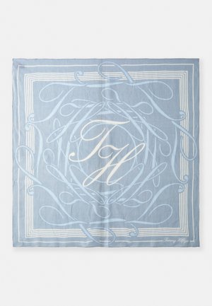 Light blue scarf with intricate white lettering and swirling patterns, featuring a bordered design and logo in the bottom corner.