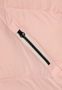 Helle rosa Pufferjacke mit einem schwarzen Reißverschluss und weißem Band. Glatte Oberfläche mit gesteppten Details. Reißverschluss-Tasche sichtbar.