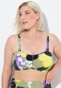 Bikini-top, joka on valmistettu venyvästä materiaalista, jossa on vihreä, keltainen ja violetti kukkakuosi. Siinä on kerrottu etuosa ja koristeelliset napit keskellä.