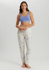 Helles, leichtes Crop-Top in Blau, kombiniert mit hellgrauen Hosen, die ein mehrfarbiges abstraktes Muster und einen elastischen Bund aufweisen.