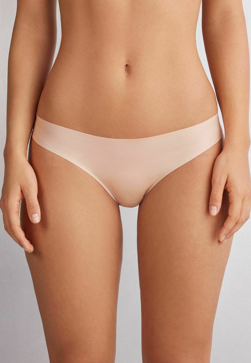 Ljust rosa bikinitrosor gjorda av slät tyg, med en sömlös design och elastisk midja. Minimalistisk form, inga synliga mönster.
