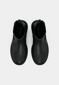 Czarne skórzane botki za kostkę o gładkim wykończeniu, zaokrąglonym nosku, elastycznych panelach bocznych i teksturowanej gumowej podeszwie. Widoczna etykieta marki wewnątrz.