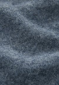 Blå ulltyg med en mjuk, texturerad yta och subtil fluffighet. Har ett stickat m�önster som tillför djup och intresse.