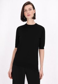 Top scurt din tricot negru cu guler rotund, textur�ă fină și o croială ușor relaxată. Purtați-l cu pantaloni negri asortați.