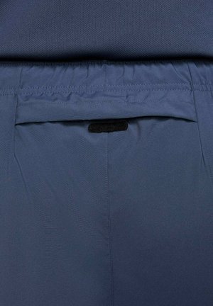 Marineblå stofshorts med en baglomme med velkrolukning. Livremmen er elastisk for komfort. Generelt glat tekstur.