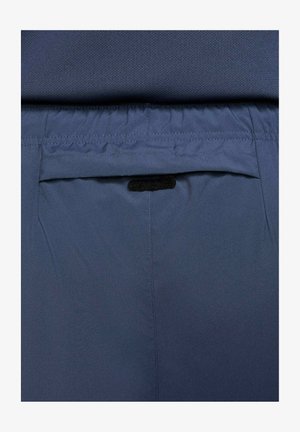 Marineblå stofshorts med en baglomme med velkrolukning. Livremmen er elastisk for komfort. Generelt glat tekstur.