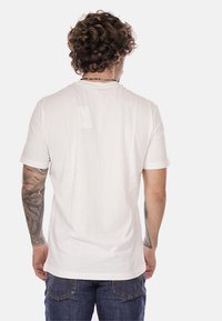 T-shirt bianco classico a maniche corte con collo rotondo, realizzato in tessuto di cotone. Caratterizzato da una texture liscia e una vestibilità casual, vista posteriore mostrata.
