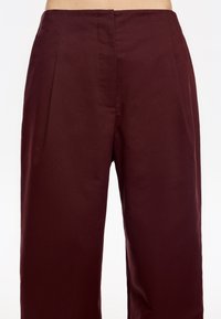 Pantalones de talle alto en burdeos con una textura suave, que cuentan con pliegues en la parte delantera y bolsillos laterales para un aspecto elegante.