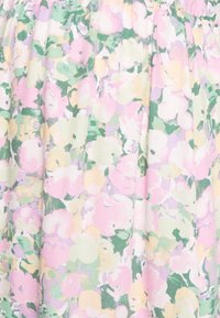 Textilie s květinovým vzorem v pastelových odstínech růžové, zelené a žluté s měkkým, texturovaným povrchem, který obsahuje skladovaný design.