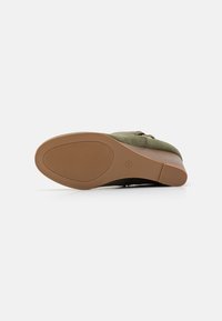 Chaussure en daim vert avec un bout rond, semelle en caoutchouc et talon bas. La semelle présente un motif de texture pour une meilleure adhérence.