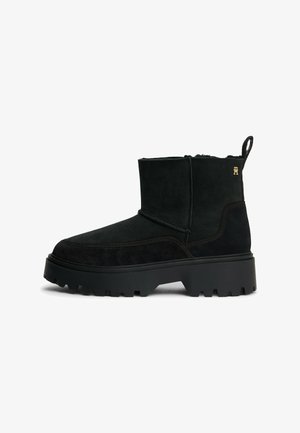 Bottines en daim noir avec un bout arrondi, une semelle en caoutchouc épaisse et un accent logo subtil. Comprend une languette pour un enfilage facile.