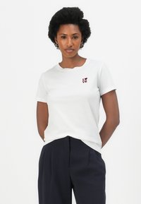 White cotton t-shirt featuring short sleeves and a crew neck, with a maroon “LOVE” graphic accent on the chest. Worn with dark trousers.