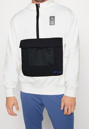 Felpa bianca con cappuccio, caratterizzata da una tasca frontale nera con pannello in rete, chiusura con zip e patch del logo Jordan. Dettaglio testuale blu sulla tasca.
