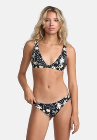 Čierny bikiny s bielym kvetinovým vzorom; trojuholníkový top a nízko strihané spodky; hladká tkanina; nastaviteľné ramienka; minimalistický vzhľad.
