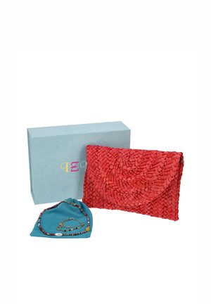 Cartera de mano roja tejida, collar de cuentas y cadena dorada expuestos junto a una caja azul claro con la marca.