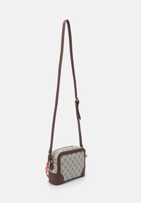Borsa a tracolla in canvas con un motivo monogramma color nocciola, dettagli in pelle marrone, hardware dorato e una tracolla regolabile. Chiusura con zip nella parte superiore.