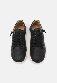 Fekete bőrsneaker, letisztult dizájnnal, hat fűzőlyukkal és sima felületű kontrasztos fehér talppal.